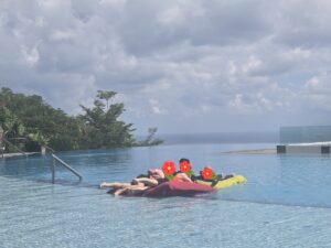 발리 리조트 수영장에서 튜브 침대를 타고 일행들과 즐겁게 웃으며 물놀이를 즐기는 모습
